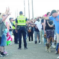Police standing to keep the peace between protesters and event attendees in line.
