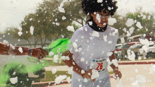 Jordan Williams tuns by the St. Clair Building and through the foam bubble blaster in the Del Mar College Color Run on Heritage Campus March 4. Photo by Victor Herrera.